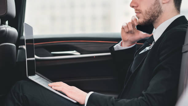 istock Businessman talking on phone in car using his pc 1252606418