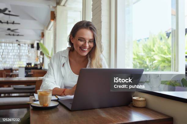 Woman Online Work At Cafe Happy Girl In Casual Clothes And Glasses With Laptop Looking At Screen Modern Digital Technologies For Remote Job Education And Comfortable Lifestyle In City Stock Photo - Download Image Now