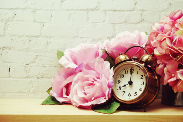 istock Alarm clock with flower decorative on white brick wall background 1252613223