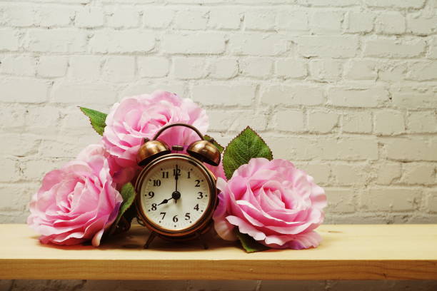 istock Alarm clock with flower decorative on white brick wall background 1252613310