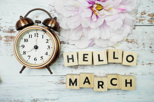 istock Hello March with alarm clock on wooden background 1252615988