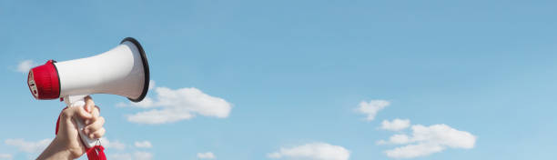 istock Hand with a megaphone against the sky. Red and white loudspeaker with copy space is power concept 1252616010