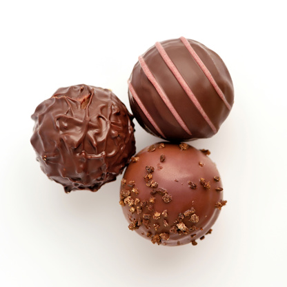 Three candies of black chocolate on white background. Top view.