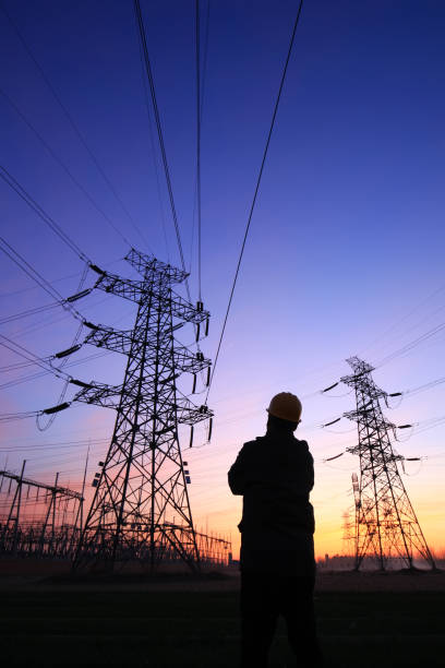 istock Electricity workers and pylon silhouette 1252617517