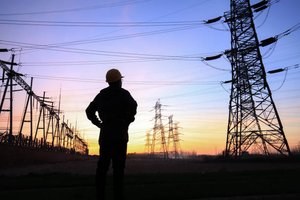 istock Electricity workers and pylon silhouette 1252617522