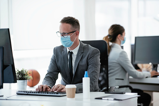 Businessman with medical mask working in office.