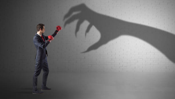 istock Businessman fighting with scary hand shadow 1252630452