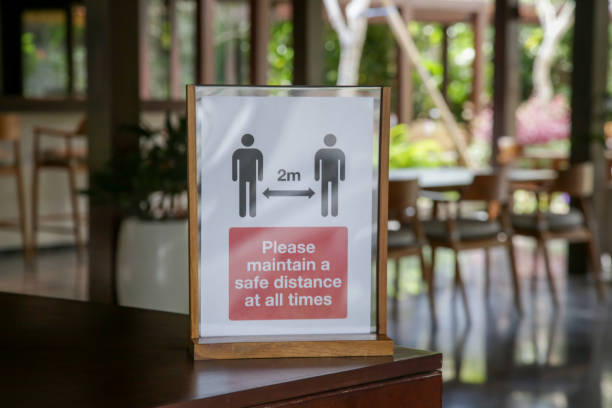 Social distancing sign at the entrance of restaurant as a reminder that everyone needs to comply with new requirements by maintaining a 2 meters distance to protect themselves and others from the Corona virus spread. señal de distanciamiento social en la entrada del restaurante como un recordatorio de que todo el mundo necesita cumplir con los nuevos requisitos manteniendo una distancia de 2 metros para protegerse a sí mismos y a otros de la propagación del virus co