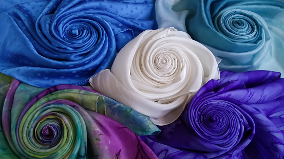 luxurious diversity of natural multi colored silk fabrics rolled in the form of a rose.