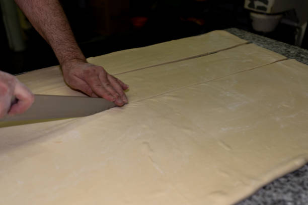 istock baker cutting the dough and then making the croissants in a bakery 1252649117