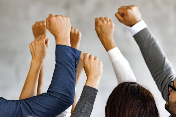 Raise your hands in protest! Large group of unrecognizable business people with raised fists. punching the air stock pictures, royalty-free photos & images