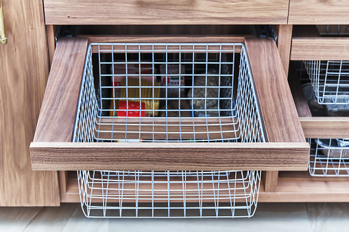 Storage organization. Metal mesh basket in wooden drawer in food storage room. Close-up