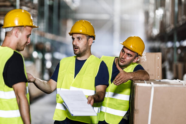 Frustrated manual workers arguing with their colleague in a warehouse.