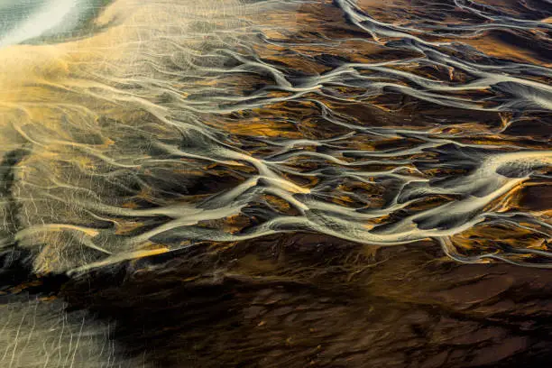 Beautiful curvatures of glacial rivers flowing through the landscape of Iceland, captured from a helicopter.
