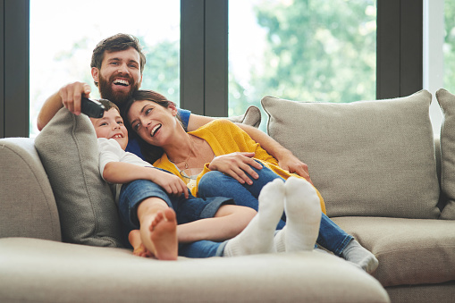 Shot of a happy family watching television on the sofa at home