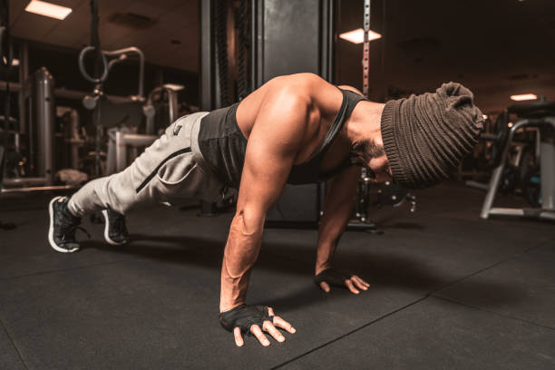 istock A sporty man in the gym is doing yoga exercises, practicing standing in the plank pose, doing push up or push up exercises, training, covered for the whole length. 1252674810