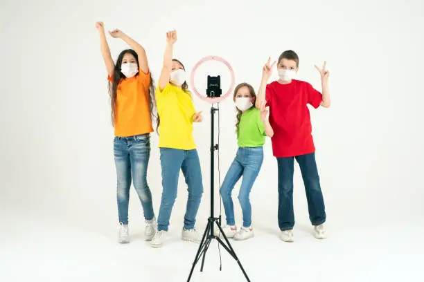 Photo of Children dance positively in medical masks. The concept of distance learning during a pandemic. Positive. Movement and sport.