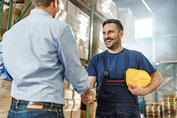 el trabajador feliz del almacén llegó a un acuerdo con su cliente. - hardhat construction men handshake fotografías e imágenes de stock