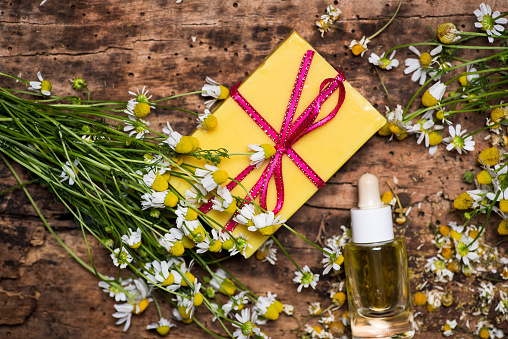 Chamomile flowers and essential oil on a wooden table top view flat lay