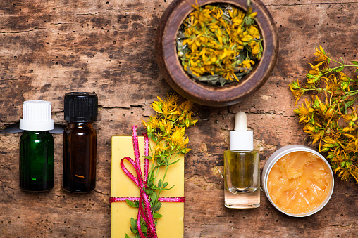 St. John's wort flowers and essential oil on a wooden table top view flat lay