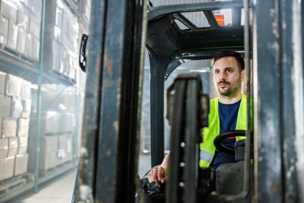 istock Manual worker driving forklift in distribution warehouse. 1252677477