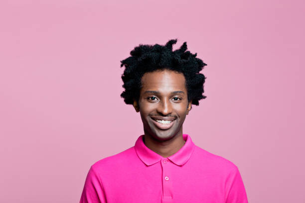 headshot de homem alegre vestindo camisa polo rosa - polo shirt african ethnicity men african descent - fotografias e filmes do acervo