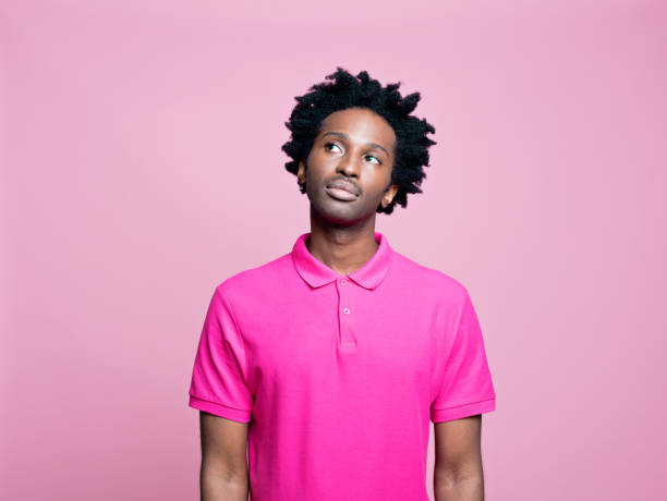 jovem pensativo vestindo camisa polo rosa - polo shirt african ethnicity men african descent - fotografias e filmes do acervo