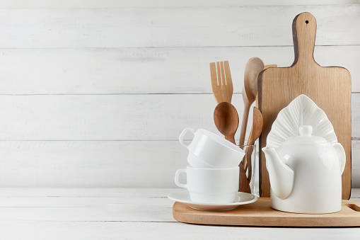 Blank space for kitchen wide banner concept. Kitchen background for mockup with spoon, teapot, cups, rolling pin, bowls on wooden table, white background.