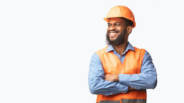 happy african builder standing pleased posing on white studio background - afro man fotografías e imágenes de stock