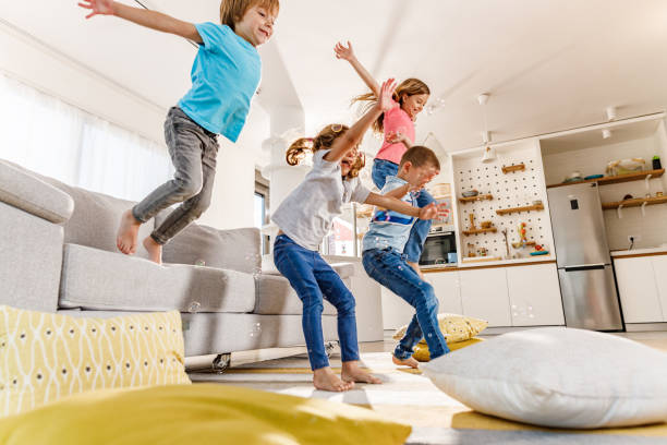 istock Playful kids having fun while jumping from sofa at home. 1252681006
