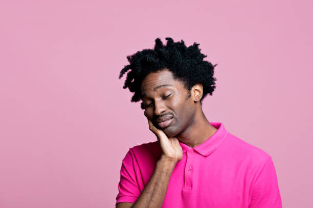 retrato de jovem preocupado vestindo camisa polo rosa - polo shirt african ethnicity men african descent - fotografias e filmes do acervo