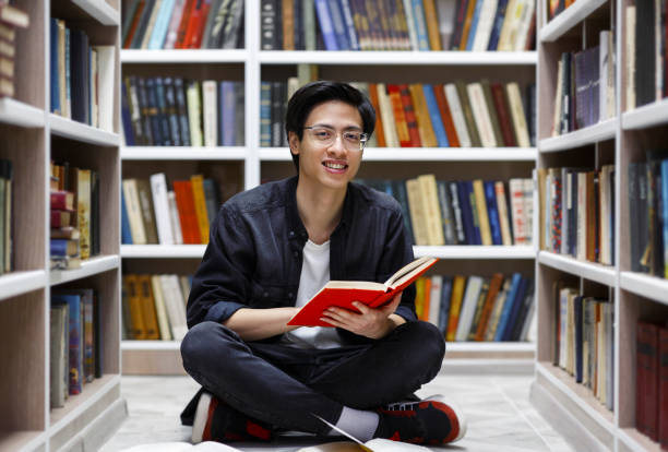 도서관에서 책을 읽는 미소 짓는 중국 남자 - bookstore student chinese ethnicity book 뉴스 사진 이미지