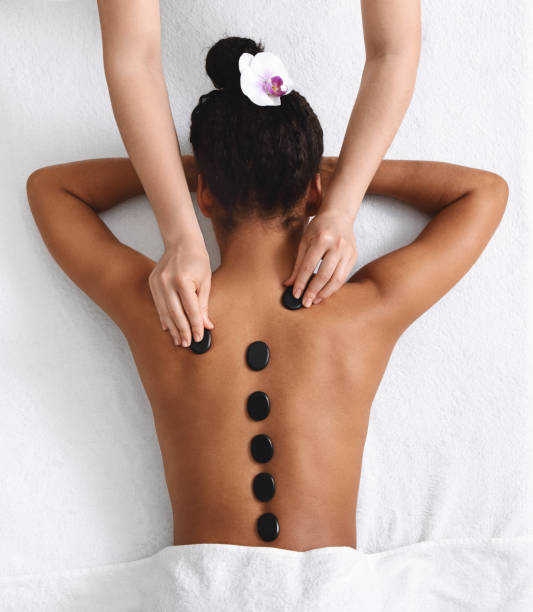 hot stone massage für junge schwarze dame, ansicht von oben - massaging spa treatment stone massage therapist stock-fotos und bilder