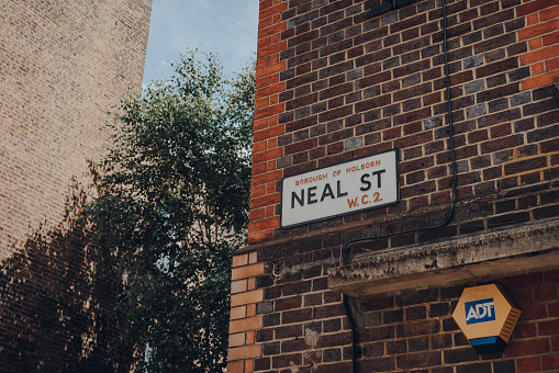 London, UK - June 13, 2020: Old street name sign on a brick wall of a building in Neal Street, Covent Garden, an area of London famous for its bars, restaurants and cafes.