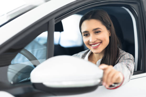 ネル車の運転席に座っている幸せな女の子 - owner women car rear view mirror ストックフォトと画像