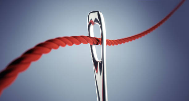 istock Close up of threading eye of a needle with red thread 1252687455