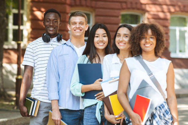 istock Group of smiling multicultural students posing near university campus 1252687685