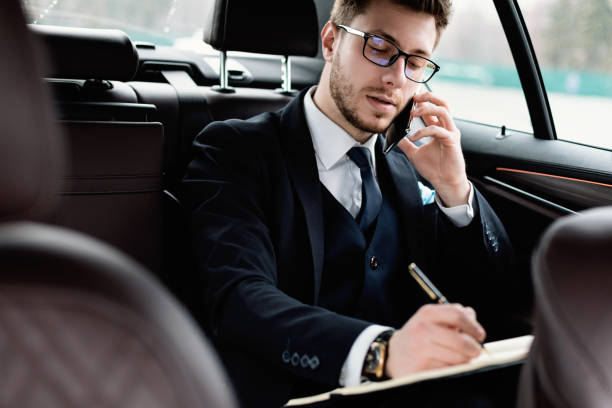 istock Businessman writing in notebook sitting in luxury car 1252691883