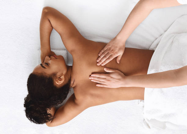 Tranquil african girl getting back massage, white background Top view of tranquil african girl getting back massage, white background massage stock pictures, royalty-free photos & images