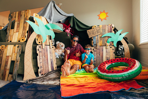 A young boy and his dad are ready to go to the beach they have made for themselves at home. The coronavirus quarantine has forced them from vacation mode to staycation mode. They are staying positive and making the best of the situation.