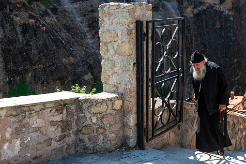 Meteora, Greece - August 22, 2014: Old Priest climbing the stairs in Meteora, Kalambaka, Thessaly, Greece.