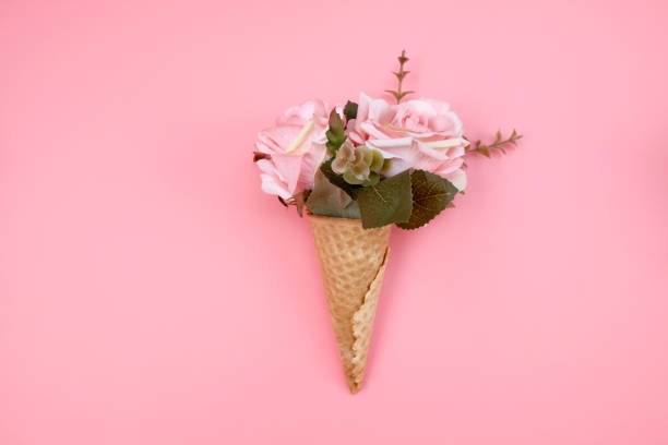 istock Waffle cone with flowers on pink background. Decorations for birthday, anniversary, wedding. Minimal decorative holiday concept. 1252696580
