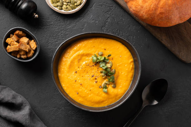 istock Pumpkin soup garnish microgreens on black. Top view. 1252696889