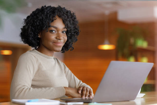 istock Smiling black lady using laptop at cafe 1252697860