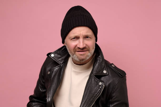 istock Serious handsome young man in leather jacket looking with doubt at camera 1252698802