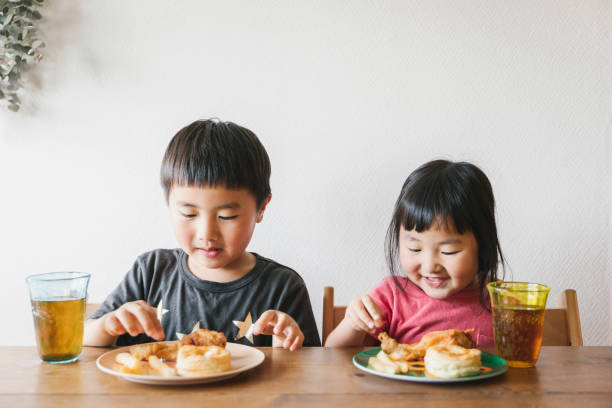 家庭で昼食を食べる子供たち - 子供時代 ストックフォトと画像