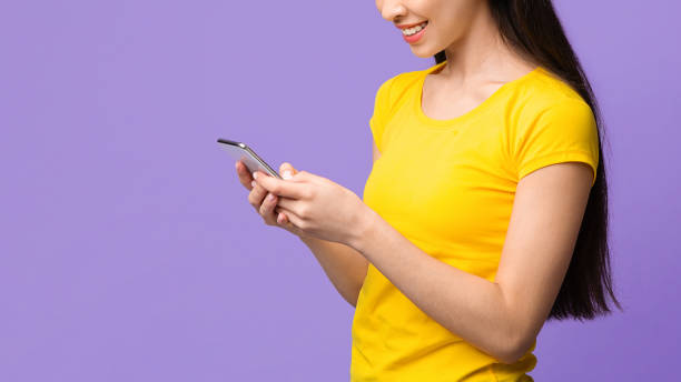 istock New useful application. Asian girl using cellphone on purple background, empty space 1252702918