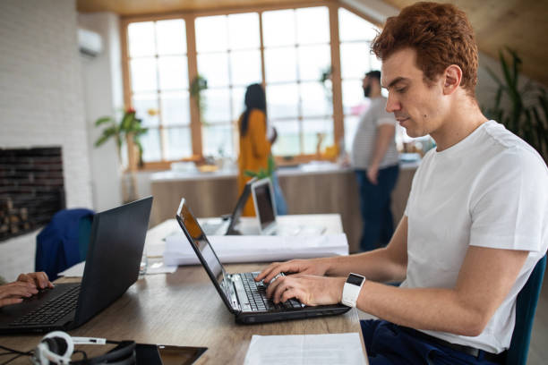 istock Redhead man sitting at table and using laptop at office 1252703413
