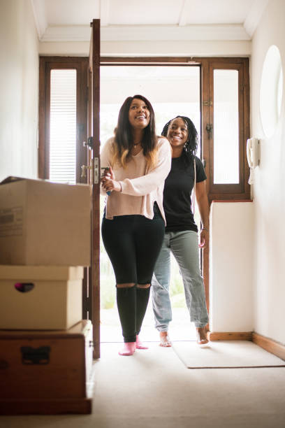 Complete walk-through of their new house Shot of two young women entering their new home from the main door gay couple photos stock pictures, royalty-free photos & images