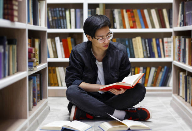 istock Focused chinese guy reading books at library 1252705689